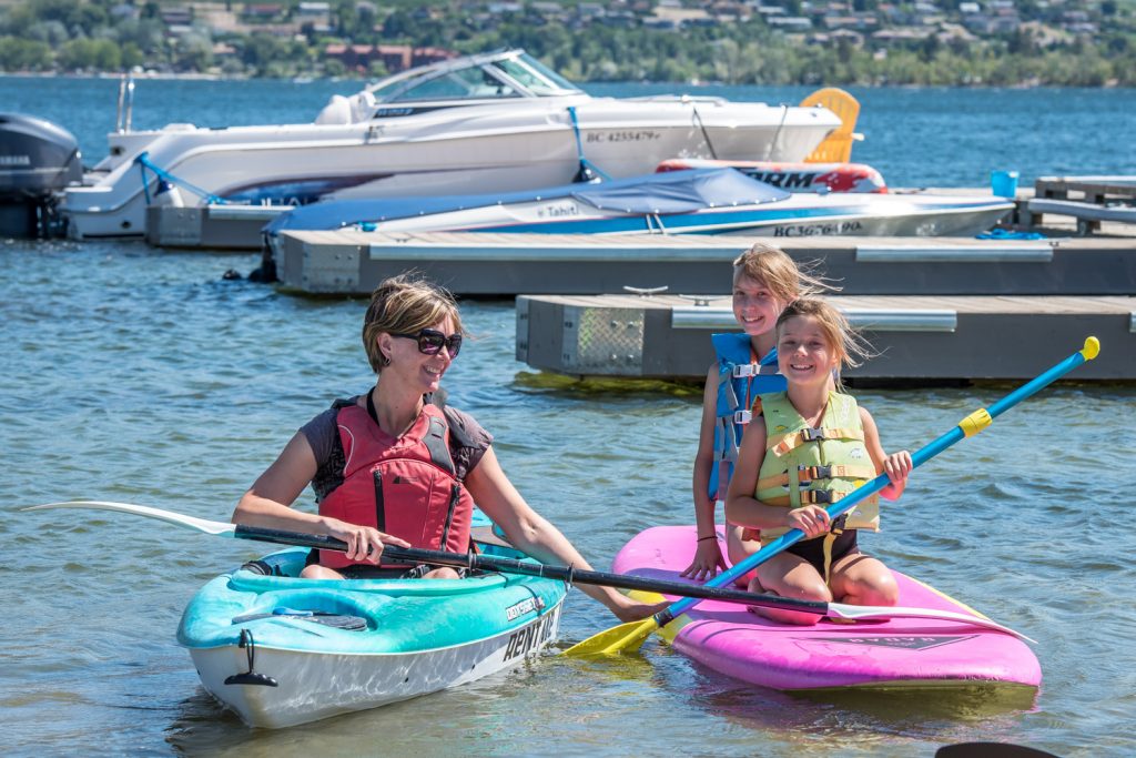 ATB Watersports held a Food for Fun event last Wednesday at Safari Beach. Those who brought food items or cash donations for the Osoyoos Food Bank were given a chance to try stand-up paddling or kayaking. Pictured are Christine Schaufert (left) and daughters Lenci and Vienne Calanchie from Abbotsford, who gave it a try. They're taking a vacation house sitting in Osoyoos. The event raised $415 in cash donations and three large totes of miscellaneous food items. (Richard McGuire photo)