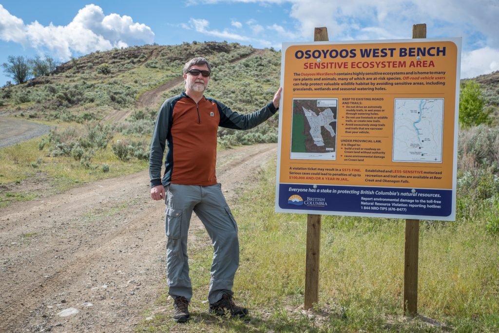 Orville Dyer, a biologist with the Ministry of Forests, Lands and Natural Resource Operations, shows a sign recently installed at the entrance to the Osoyoos West Bench. The sign warns of the sensitive ecosystem and asks users of off-road vehicles to avoid sensitive areas. The ministry hopes to educate ATV users about this habitat. (Richard McGuire photo)