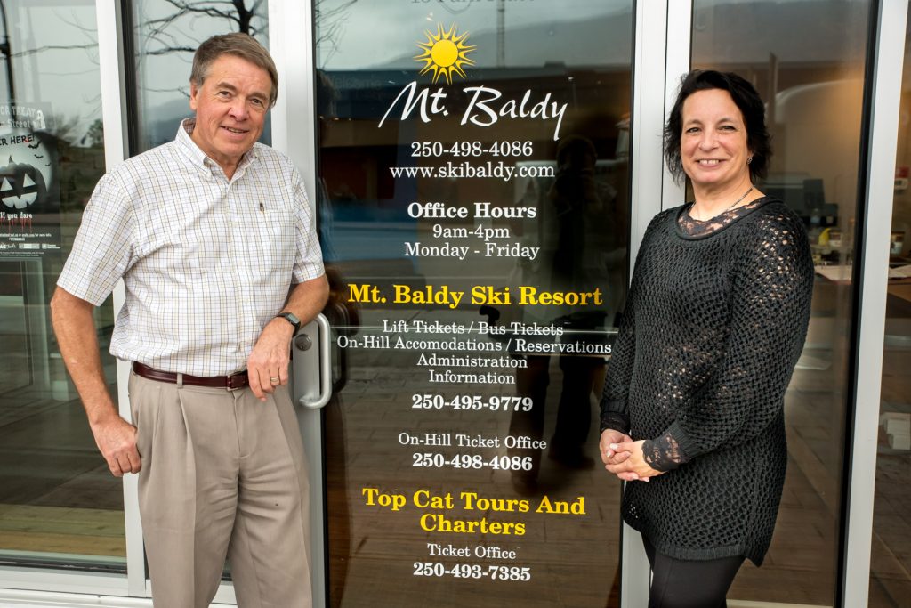 Fred Johnston, president of Baldy Capital Corporation, poses with Melanie Zane, food and beverage manager, at the new office for Mount Baldy in Osoyoos. The office opens this week in the former Landsea Okanagan office at the Watermark Beach Resort. Johnston announced plans to run a daily bus service to the ski resort, have Saturday entertainment and develop an accommodation system. (Richard McGuire photo)