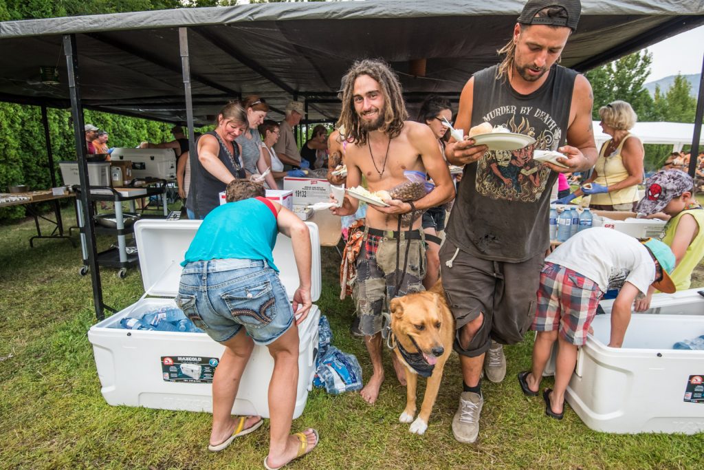 Guillaume Bégin, of Sherbrooke, Quebec, carries a bag of food given to him for his dog when Osoyoos Baptist Church served dinner to migrants last week. Max Pelissier (right) carries away a dinner for himself. (Richard McGuire photo)