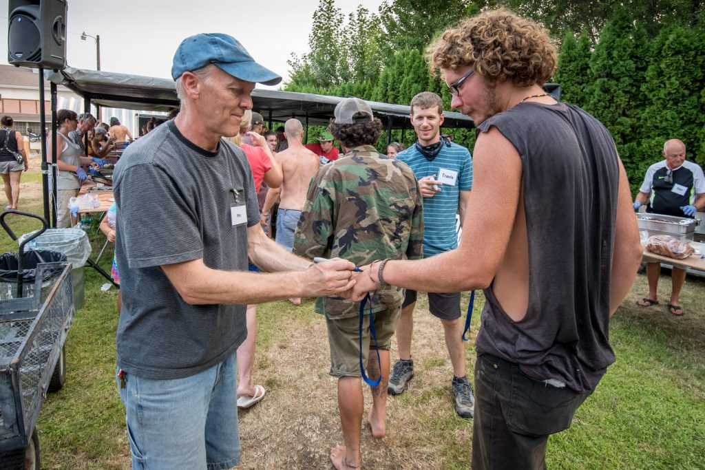 Pastor Phil Johnson, of Osoyoos Baptist Church, marks the hand of a migrant as he goes up to eat. This is to prevent people from returning for more before seconds are announced. (Richard McGuire photo)