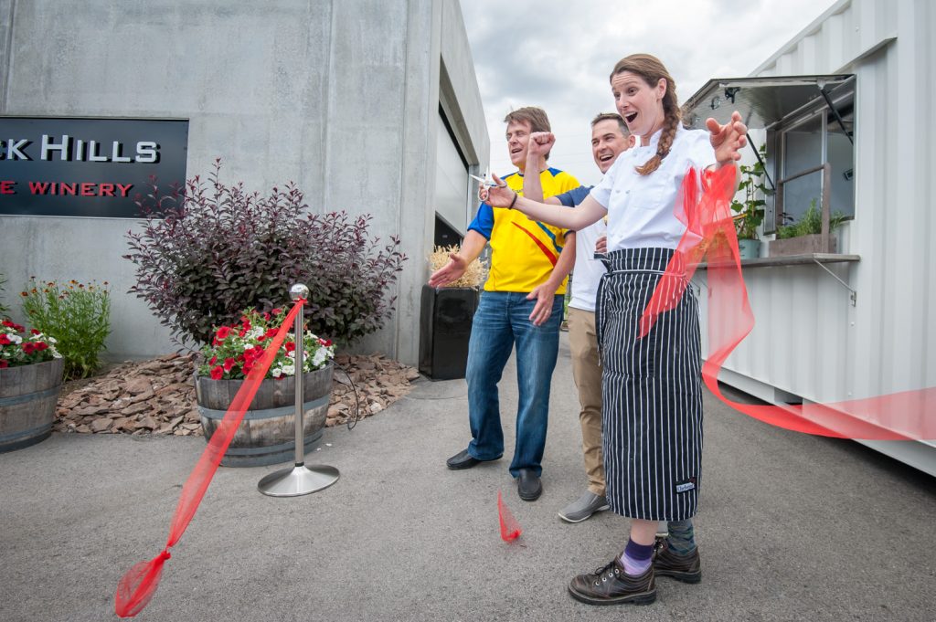 Dana Ewart, right, co-owner of Joy Road, cuts the ribbon while Black Hills President Glenn Fawcett (left) and Winemaker Graham Pierce look on. (Richard McGuire photo)