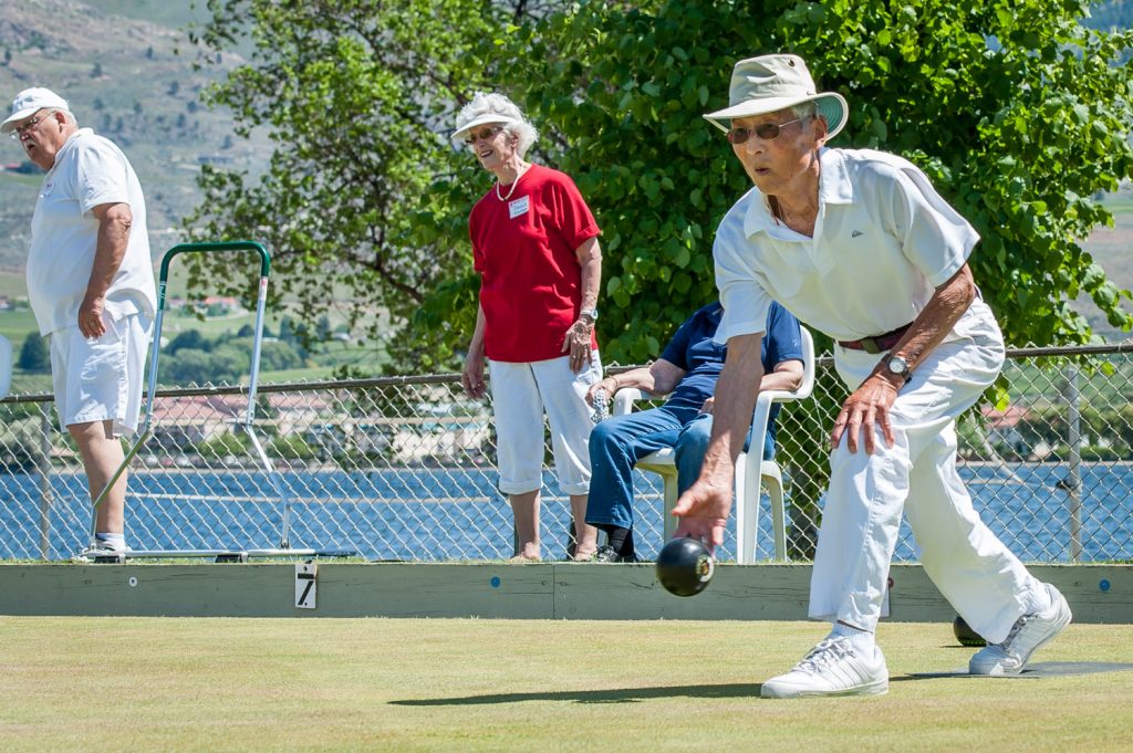 Naga Terada, president of the Osoyoos Lawn Bowling Club, bowls during Saturday's Open House event while Jessie Smythe watches in the background. The tournament drew bowlers from other parts of the Okanagan and beyond. (Richard McGuire photo)