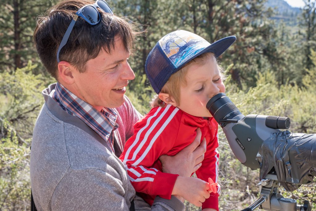 John Pushor helps his son Harvey, 5, look through a telescope at burrowing owls being raised by the Burrowing Owl Conservation Program. The birds are in a large cage and people are kept back at a distance so as not to upset them. The Burrowing Owl Conservation Program is a separate organization from SORCO, the Raptor Rehab Centre, but they share the same property. Both organizations invited the public to see their operations at an open house on Sunday. (Richard McGuire photo)
