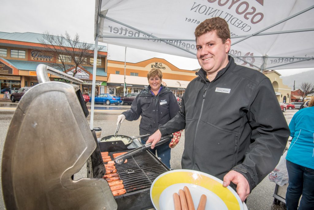 Osoyoos Credit Union was serving hot dogs and other refreshments on Thursday in front of their branch in celebration of International Credit Union Day. Dedicated volunteers braved the drizzle to work the barbecues. Pat Wycherley (background) and Zachary Poturia are both directors who were helping out at lunch. (Richard McGuire photo)