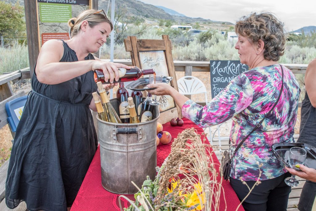 Roberta Snow (left) of Rustic Roots Winery pours a glass of organic cherry wine for a guest at one of the stops along the boardwalk at Romancing the Desert on Saturday evening. (Richard McGuire photo)