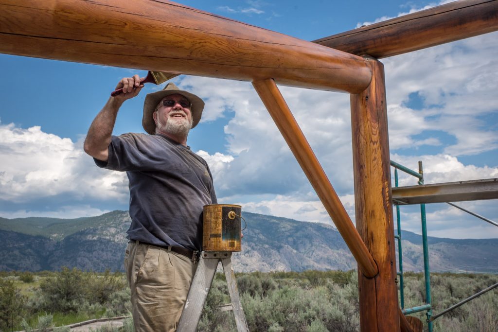 Peter Beckett, a volunteer and board member with the Osoyoos Desert Society, applies a finish to one of the kiosks at the Desert Centre. Last week more than 10 volunteers turned out to restore four kiosks and two sign stations, applying new finish to protect the wood. The work was expected to be completed by this week. (Richard McGuire photo)