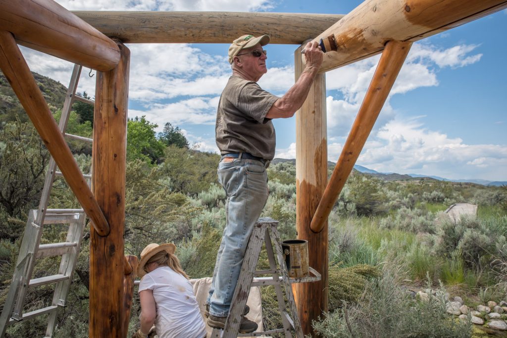Tom Gee (right) and Leahann Nordin, volunteered last week at the Osoyoos Desert Centre to apply a finish to one of the kiosks. Last week more than 10 volunteers turned out to restore four kiosks and two sign stations, applying new finish to protect the wood. The work was expected to be completed by this week. (Richard McGuire photo)