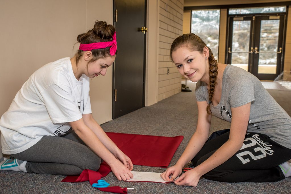 Emma Fernandes (left) plays Lumiere and Hannah Shiels plays Belle in the Osoyoos Secondary School Drama Club's upcoming production of Beauty and the Beast. Shown here, the two cut materials for costumes. (Richard McGuire photo)