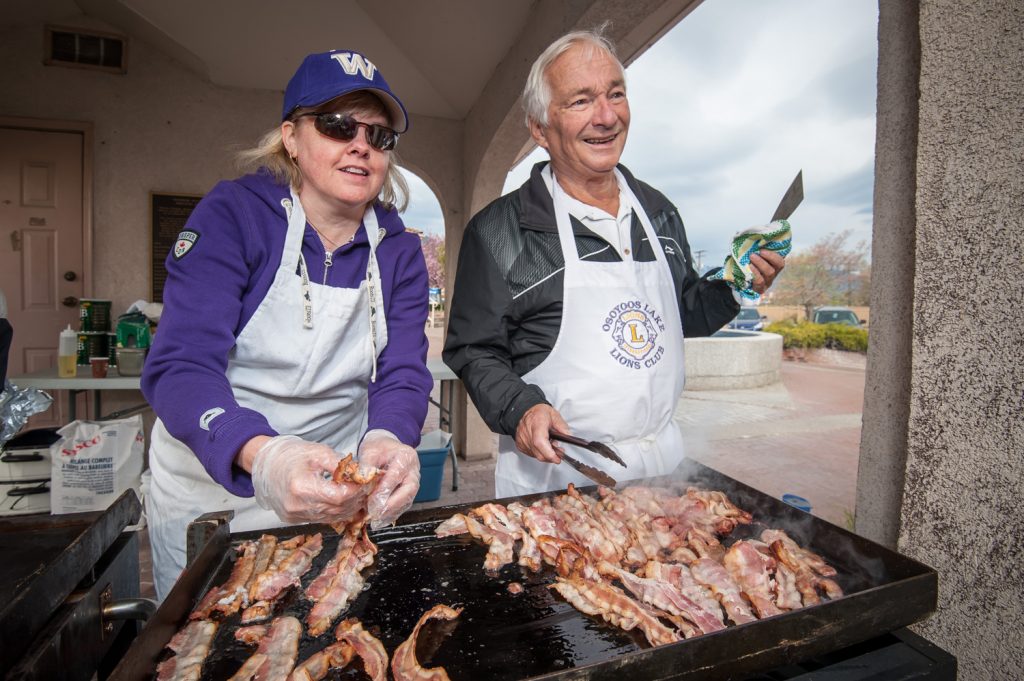Easter Eggstravaganza kicked off with the Rotary Pancake Breakfast at Town Square. Rotary took this event over from the Lions Club after the Lions disbanded, and Rotary inherited some of the Lions' equipment, including the apron worn by Rotarian Roger Clinton (right). Also helping is volunteer Sheila Lown. (Richard McGuire photo)
