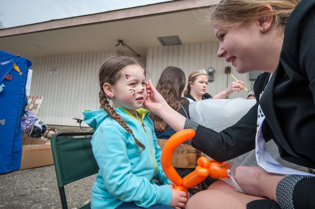 Amara Leeson (right) a contestant for the Osoyoos Royalty, paints the face of six-year-old Emily Caldwell of Okanagan Falls. The five new Royalty contestants did face painting, ran a fish pond and handed out candy during the parade at Easter Eggstravaganza. (Richard McGuire photo)