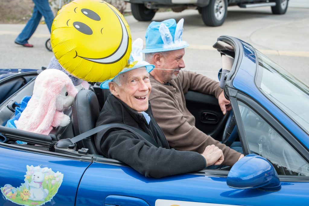 Councillor Michael Ryan (passenger seat) smiles like the happy face balloon above his head while fellow councillor C.J. Rhodes keeps his eye on the road. The two travelled by convertible during Saturday's Easter parade. (Richard McGuire photo)