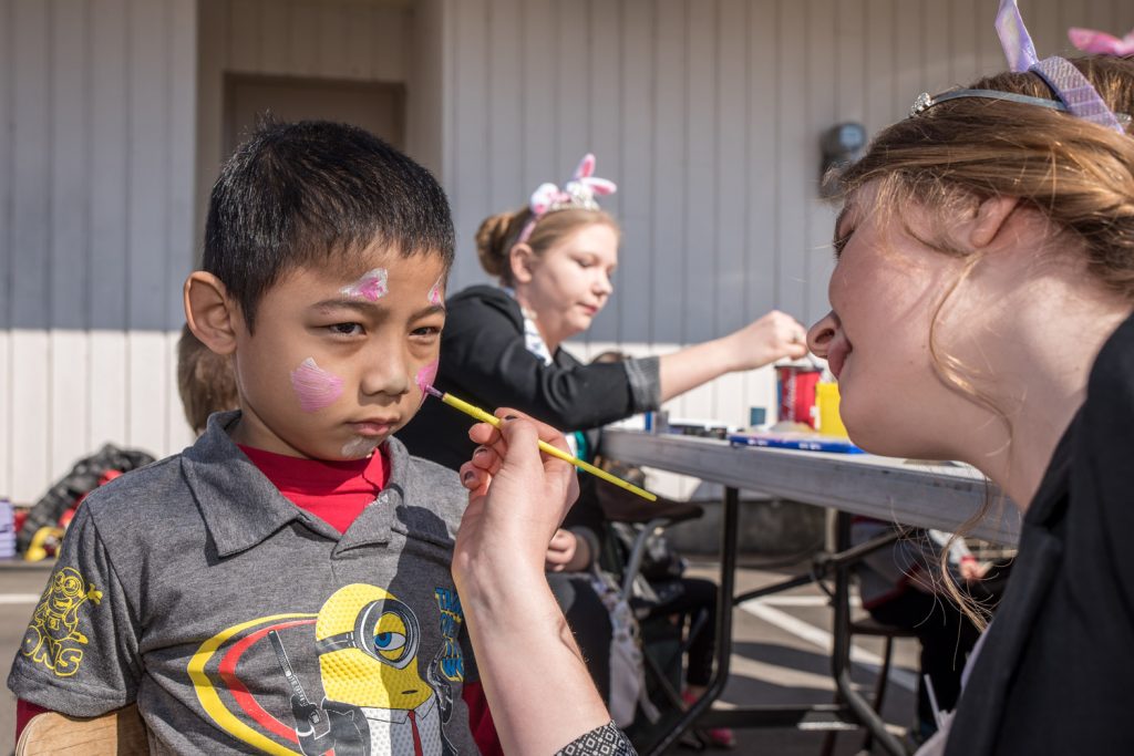 Christian Urdas, 7, of Osoyoos, gets his face painted by Ali Hutter, an Osoyoos Royalty princess. In the background, fellow princess Amara Leeson, works on the face of another child. (Richard McGuire photo)