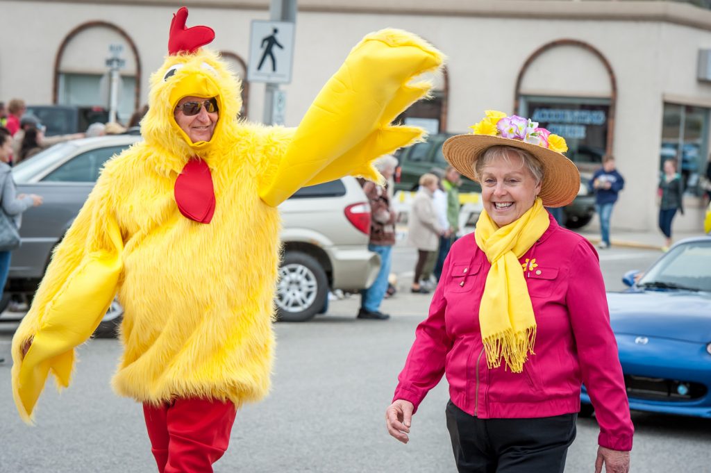 A yellow and red chicken resembling Osoyoos Mayor Stu Wells walks with Councillor Sue McKortoff, dressed in red and yellow. The two walked the length of the Easter parade route Saturday while fellow council members Michael Ryan and C.J. Rhodes drove. (Richard McGuire photo)