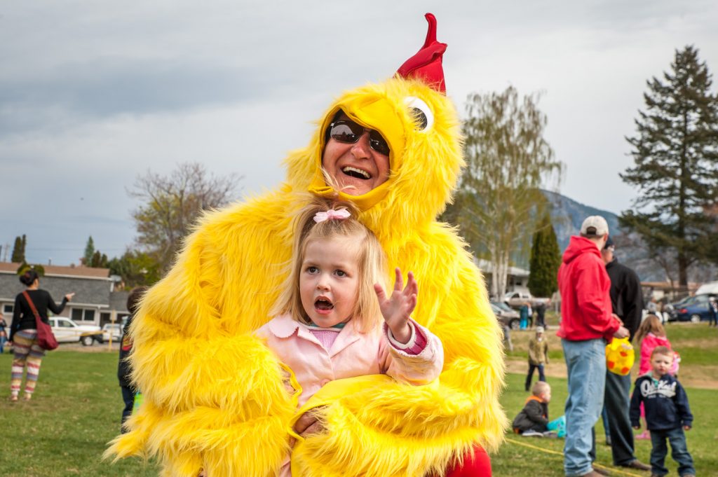Little Sayde Khan is engulfed in the feathery wings of a giant chicken. The chicken closely resembled Osoyoos Mayor Stu Wells. The chicken greeted and posed with many young children after the Easter egg hunt at Easter Eggstravaganaza. (Richard McGuire photo)