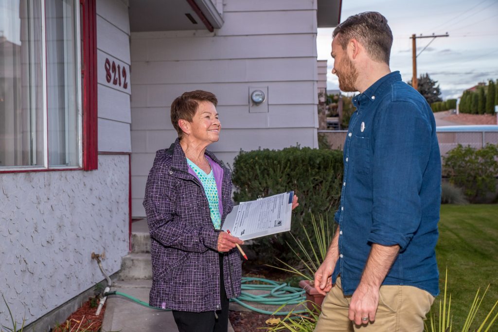 Adam Lynes-Ford (right) chats with Gravenstein Drive resident Donna Flintoft as he asks her to sign a pledge to consider health care when she casts her ballot in the Oct. 19 federal election. He didn't need to twist her arm. She's a retired nurse who was once regional vice president with the B.C. Nurses Union and she had a big NDP sign on her lawn. (Richard McGuire photo)