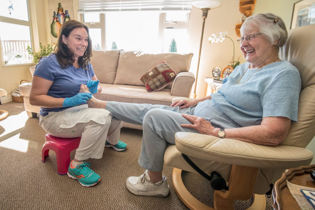 Kristen Garner (left) shares a laugh with customer Marge MacLeod of Osoyoos as she works on her feet. (Richard McGuire photo)