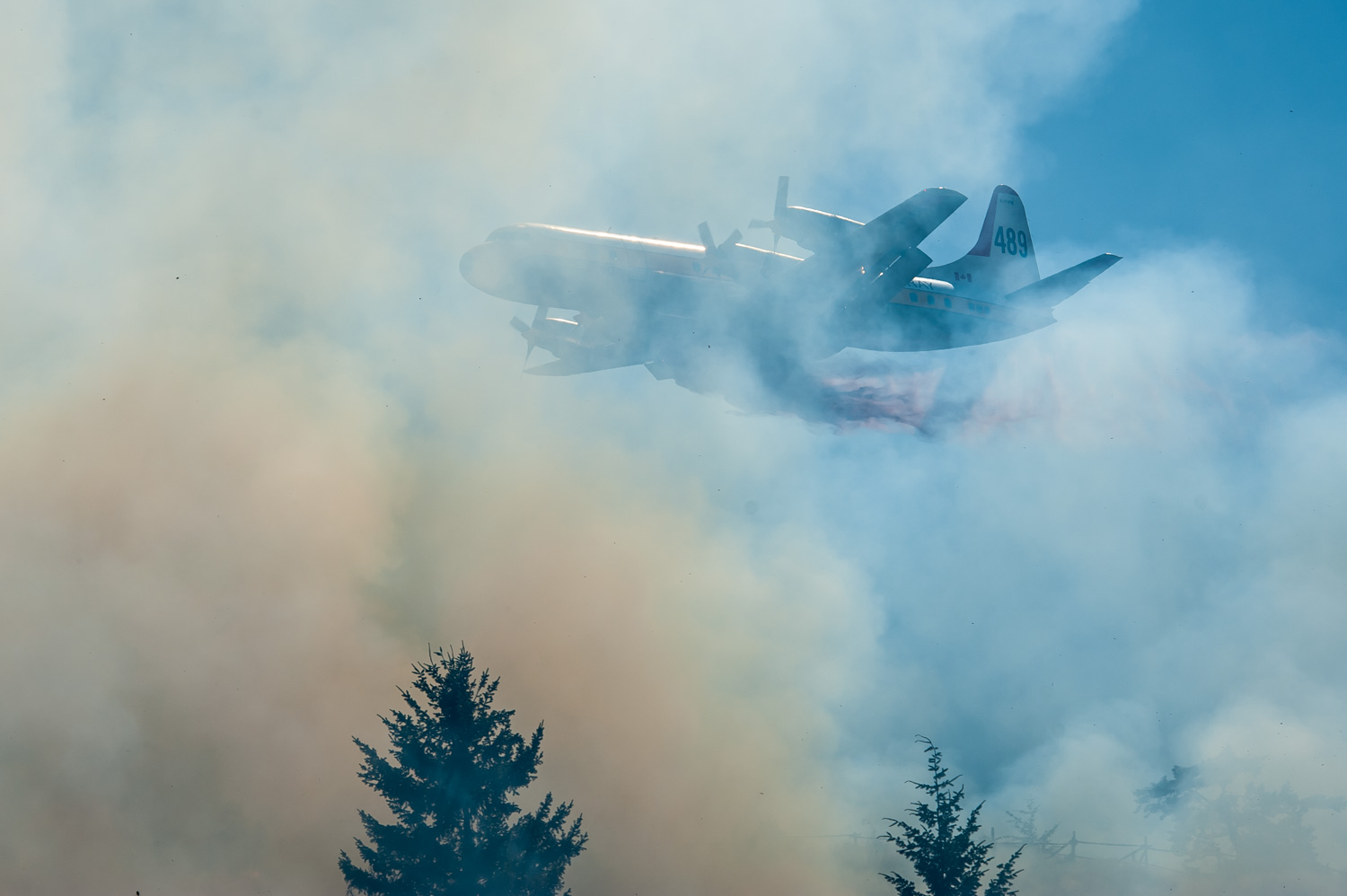 A tanker plane starts dripping fire retardant as it flies into a thick cloud of smoke at a recent wildfire near Osoyoos. Most fires have been human caused like this one probably caused by a cigarette. (Richard McGuire file photo)