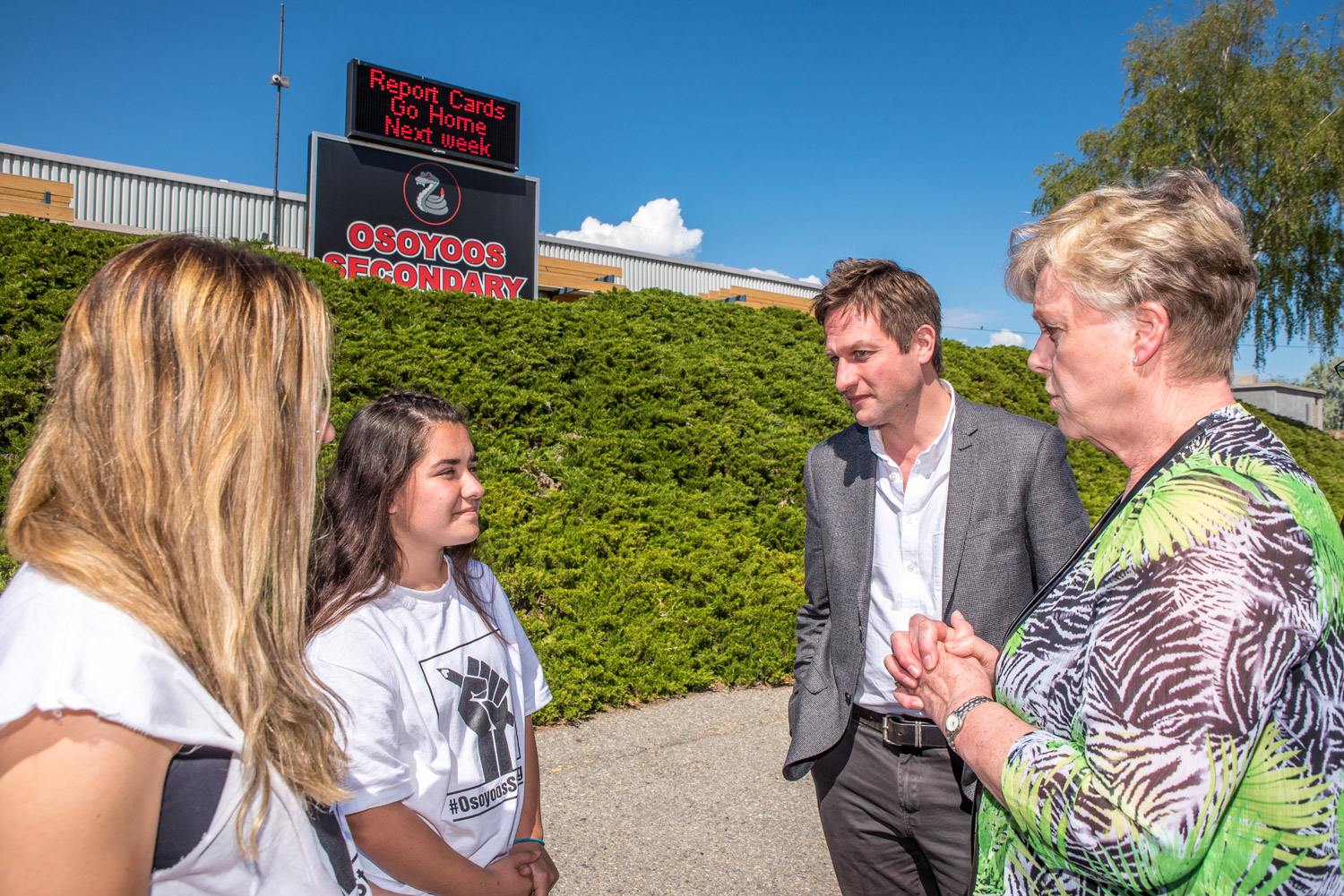 NDP Education Critic Rob Fleming (second from right) and Mayor Sue McKortoff (right) congratulate Osoyoos Secondary School students Julianna Riznek and Natalia Ibanez for taking the intitiative to create a "Thank You" banner for the Osoyoos community. (Richard McGuire photo)