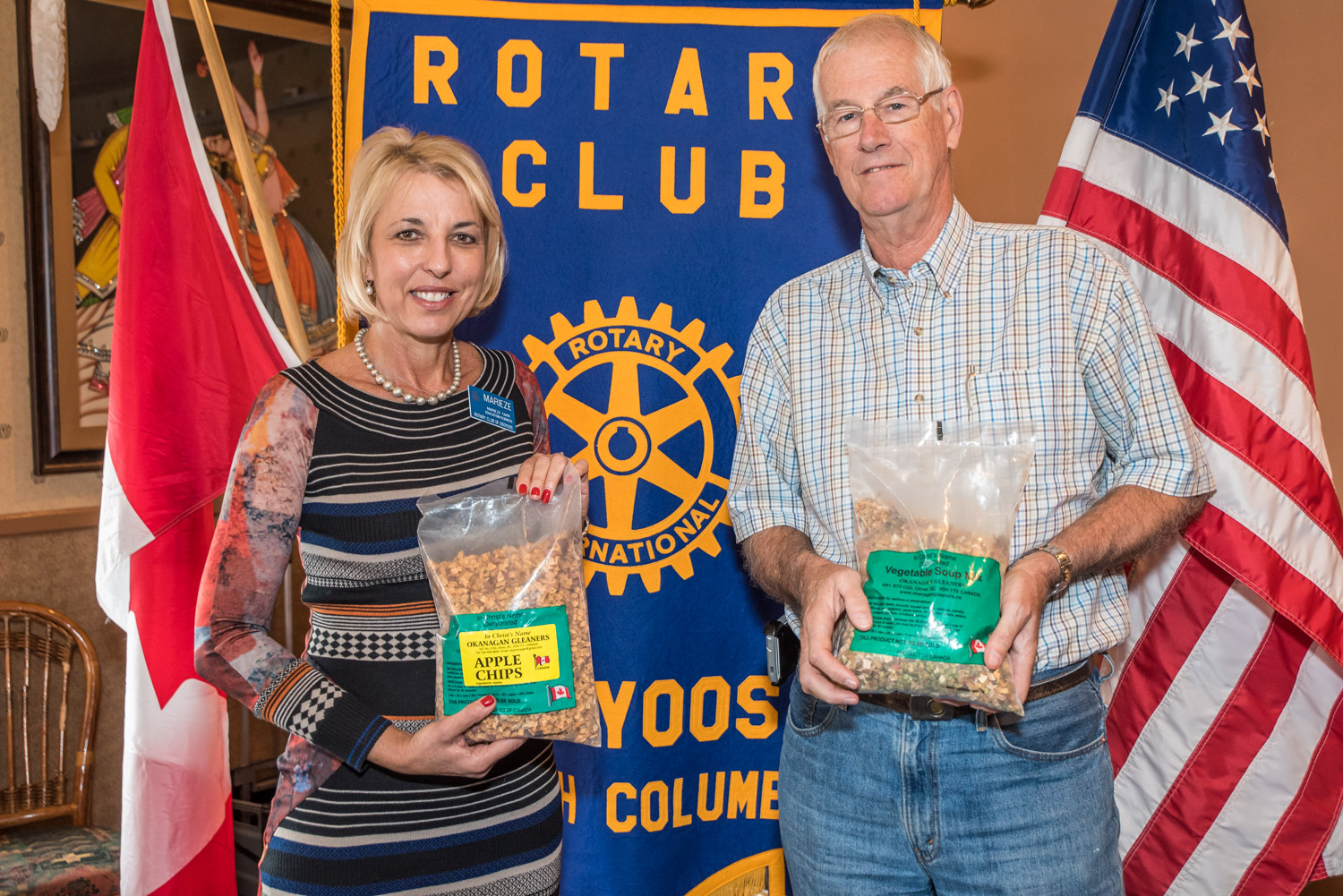 Bill Saul (right), a board member with the Okanagan Gleaners, was guest speaker at the Rotary Club of Osoyoos last week. He shows off a bag of vegetable soup mix made by the Gleaners while Marieze Tarr, Rotary president, holds a bag of apple chips, which are a treat for children overseas. (Richard McGuire photo)