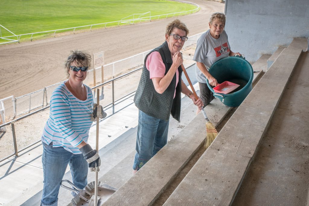 Volunteers (from left) Roberta Hormes, Darla Flack and Gail Hochsteiner were busy on Saturday cleaning up the bleachers at Desert Park in preparation for two horse race days in August. Although the bleachers were rebuilt this summer, there was an accumulation of dirt and bird droppings. (Richard McGuire photo)