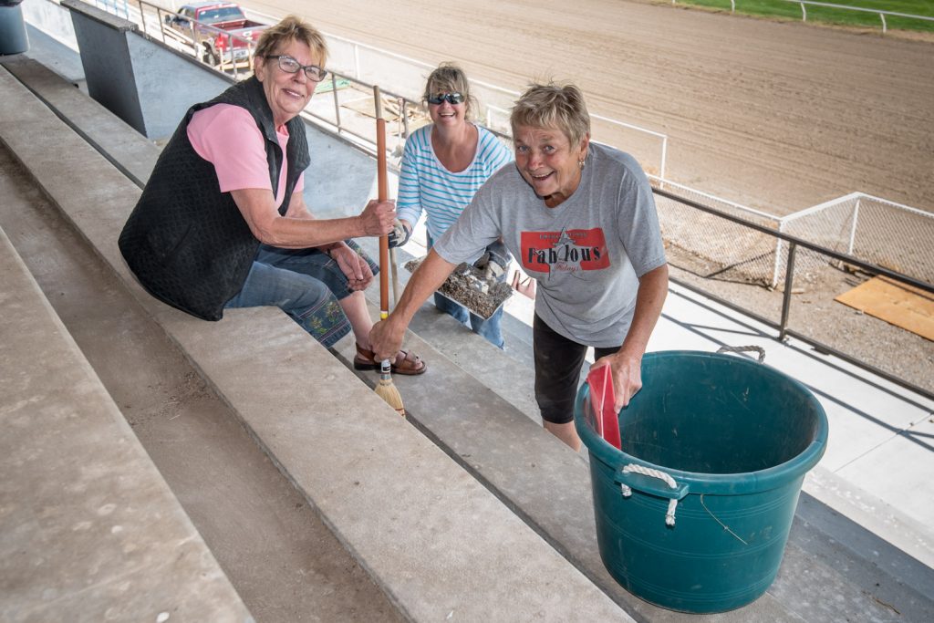 Volunteers (from left) Darla Flack, Roberta Hormes and Gail Hochsteiner were busy on Saturday cleaning up the bleachers at Desert Park in preparation for two horse race days in August. Although the bleachers were rebuilt this summer, there was an accumulation of dirt and bird droppings. (Richard McGuire photo)