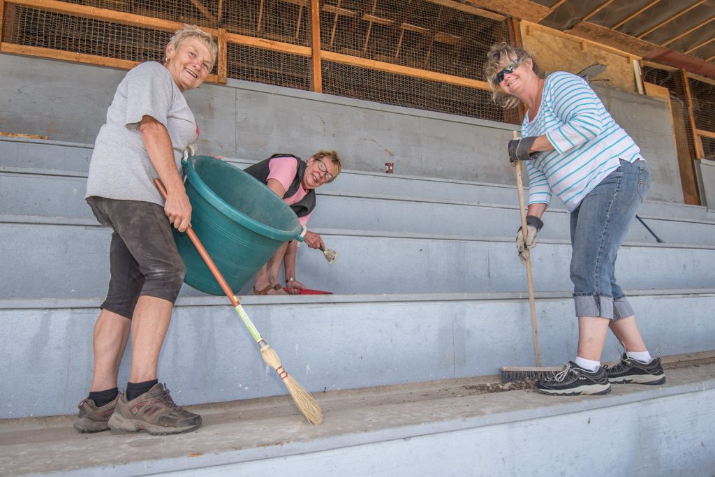 Volunteers (from left) Gail Hochsteiner, Darla Flack and Roberta Hormes were busy on Saturday cleaning up the bleachers at Desert Park in preparation for two horse race days in August. Although the bleachers were rebuilt this summer, there was an accumulation of dirt and bird droppings. (Richard McGuire photo)