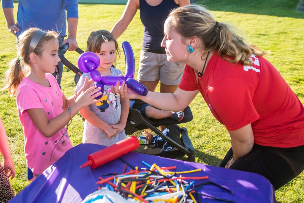Jazz Humphries (right) of Par T Perfect hands a dog balloon to Kendall Mullen-Knight (left), 7, while her sister Courtney, 5, looks on. They were among the hundreds of Osoyoos residents celebrating the revamping of Gyro Park last Wednesday. (Richard McGuire photo)