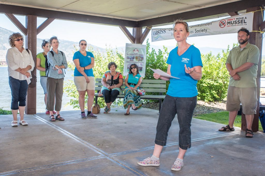Lisa Scott, co-ordinator of the Okanagan and Similkameen Invasive Species Society (OASISS) welcomes guests from both sides of the border to Weeds Cross Borders 2015 Celebration at Cottonwood Park. A number of people spoke about invasive species at the event that celebrated 10 years of formal cross-border collaboration. (Richard McGuire photo)