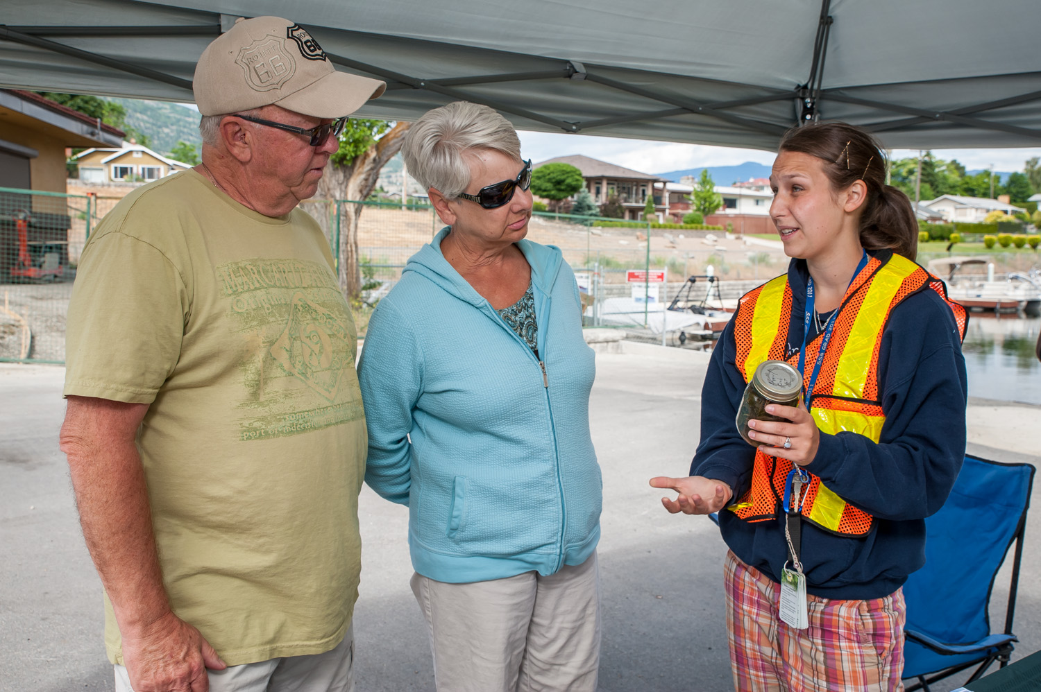 Savanna Maddock, right, is a summer student working for the Okanagan and Similkameen Invasive Species Society (OASISS) to inform the public about aquatic invasive species. On Sunday, as part of Invasive Species Week, she was at Desert Sun Marina where she spoke with Neil and Darlene Lillies of Osoyoos. (Richard McGuire photo)