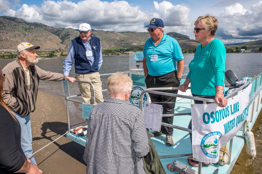 Denis Potter (second from left) and Brian Faltinson (second from right) show off the boat and equipment used by the Osoyoos Lake Water Quality Society. They answered questions from Jacob de Raadt (left) and other members of the public while Mayor Sue McKortoff (right) listens. (Richard McGuire photo)
