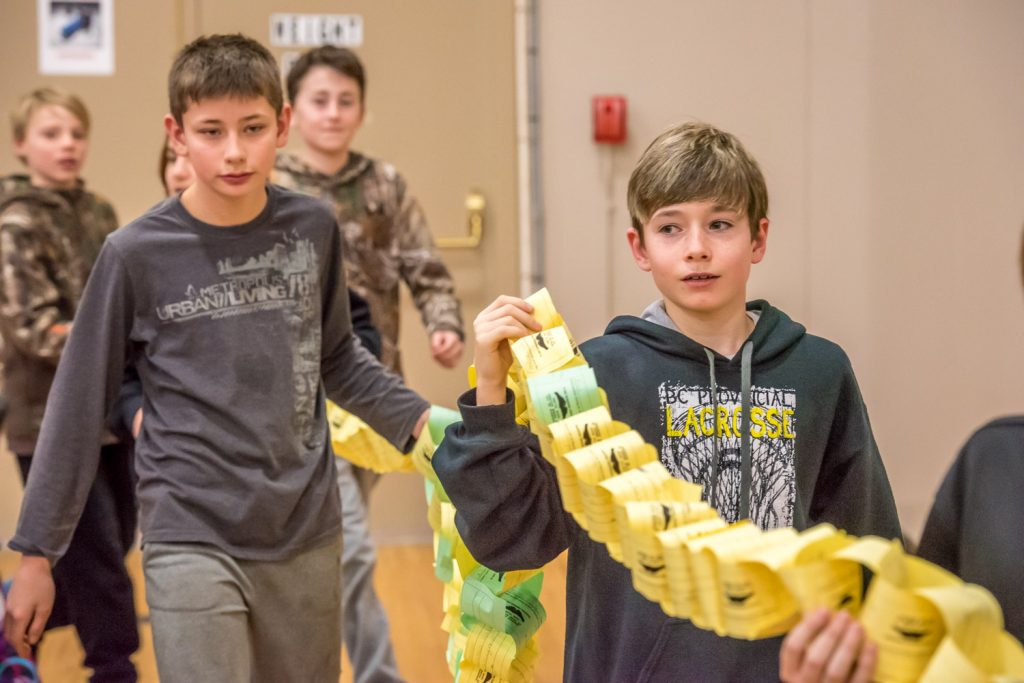 Students bring a "chain of kindness" down from the bleachers to circle their fellow students. Pictured in the foreground are Jeremy Collier and Brayden Aldridge. (Richard McGuire photo)