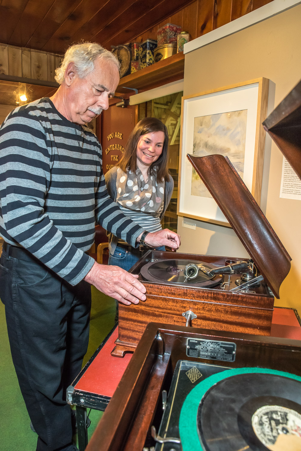 Allan Gaudreault show the Victor VV-IX "Victrola" tabletop phonograph he restored for Osoyoos Museum, while Manager Kara Burton looks on. In the foreground is an older Edison A-100 diamond disc player that he also restored. It plays 80 rpm records made of wood fibre and resin and coated with shellac. The phonographs will be playing when the museum holds an open house on Saturday. (Richard McGuire photo)