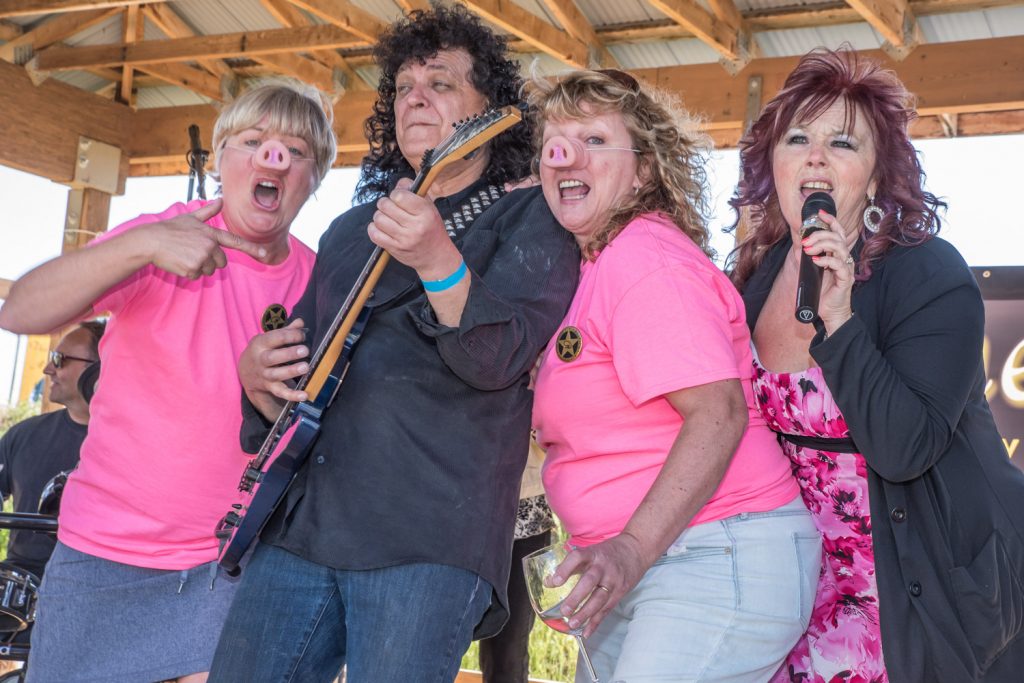 Wearing pig noses, Helen Tidder (left) and Cheryl Trsek (third from left) joined others on stage at the end of Pig Out on Saturday where Wined It Up, a cowboy rock band was performing. Guitarist Ken Repkow and singer Mikie Spillett performed some lively music for the two pigs and other guests, who were up dancing. Tidder and Trsek were visiting from the Lower Mainland. (Richard McGuire photo)