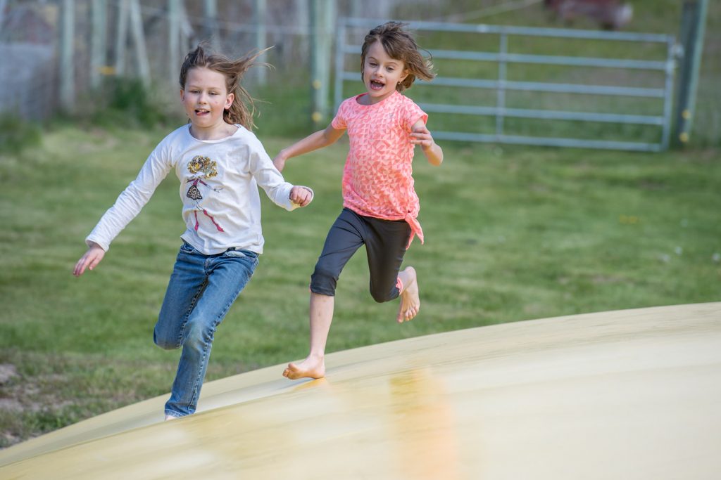 Young girls have fun bouncing around on a Jumping Pillow at Pig Out on Saturday at Covert Farms. Pictured are Caitlin Keeler (left) from Penticton and Jennifer Vallee from Richmond. (Richard McGuire photo)