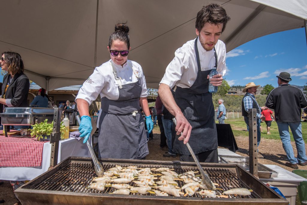 Jenna Pillon (left) and Marcus Elliott of Terrafina Restaurant at Hester Creek turn over some delicacies of stuffed baby squid. They were among the chefs participating in Pig Out at Covert Farms north of Oliver on Saturday. Visitors could pair local wines with food prepared by the region's best chefs. (Richard McGuire photo)