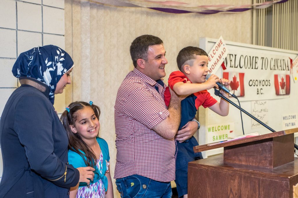 Mohamad holds up Samer, who gave an enthusiastic "Thank you" at the microphone. Mother Aya and daughter Fatima look on. (Richard McGuire photo)