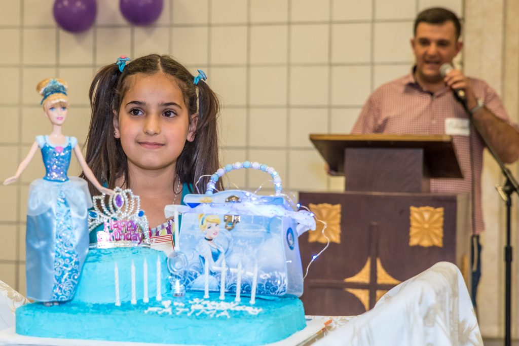 Fatima, who turned nine on Sunday, stands behind her elaborately decorated cake while people sing "Happy Birthday" to her in English and Arabic. (Richard McGuire photo)