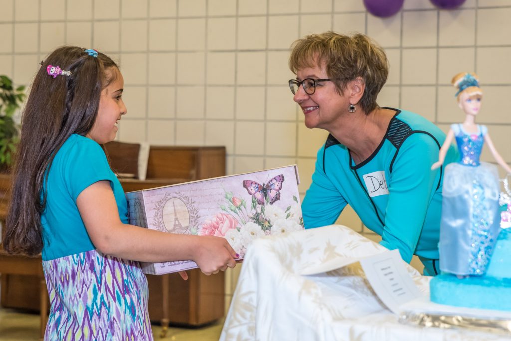 Committee member Deb Holoboff hands a present to Fatima for her ninth birthday. It's a handmade "bamboletta" or doll made from natural fibres. (Richard McGuire photo)
