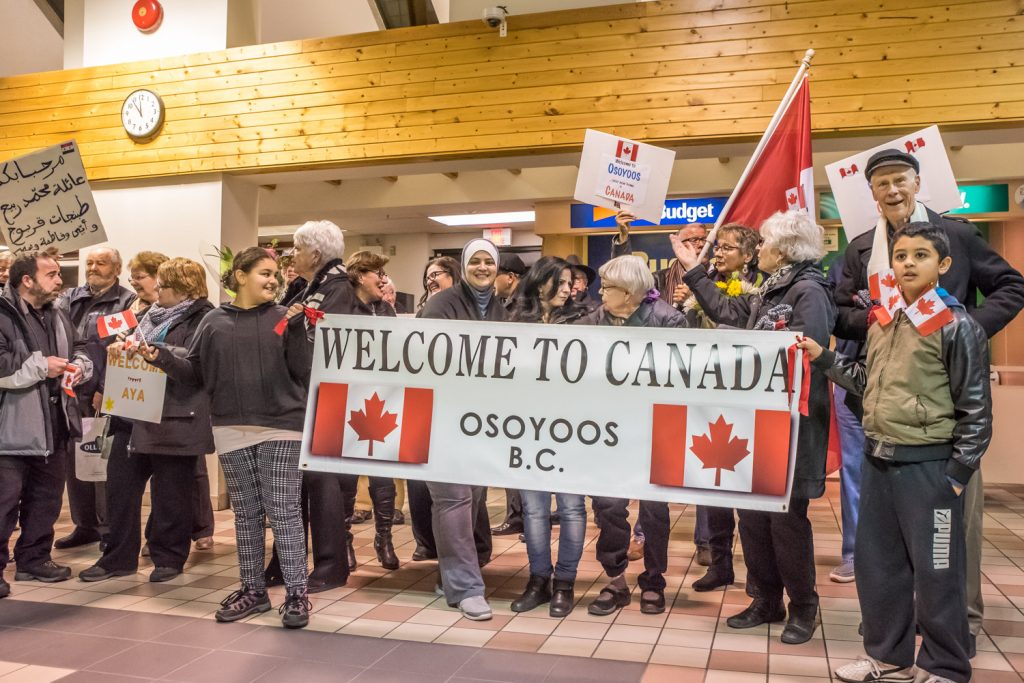 More than 30 people from Osoyoos and other communities came to the airport in Penticton to welcome the arrival of a Syrian Refugee family, the Tabanjats, who have been sponsored to come to Osoyoos. They brought signs and banners in English and Arabic welcoming the family. The family was overwhelmed and kept expressing thanks. (Richard McGuire photo)