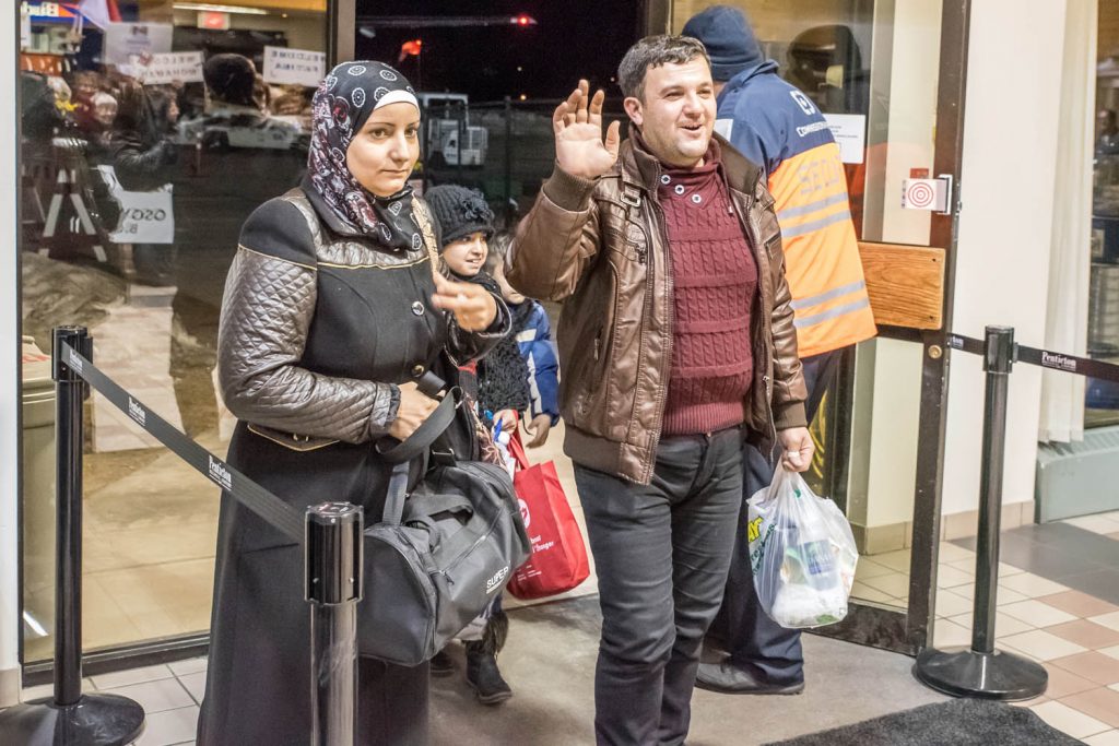Mohamad Rabee Tabanjat waves last January as he realizes the large welcome party is meant for his family. With him are his wife Aya and behind are their children Fatima, 8, and son Samer, 6. (Richard McGuire photo)