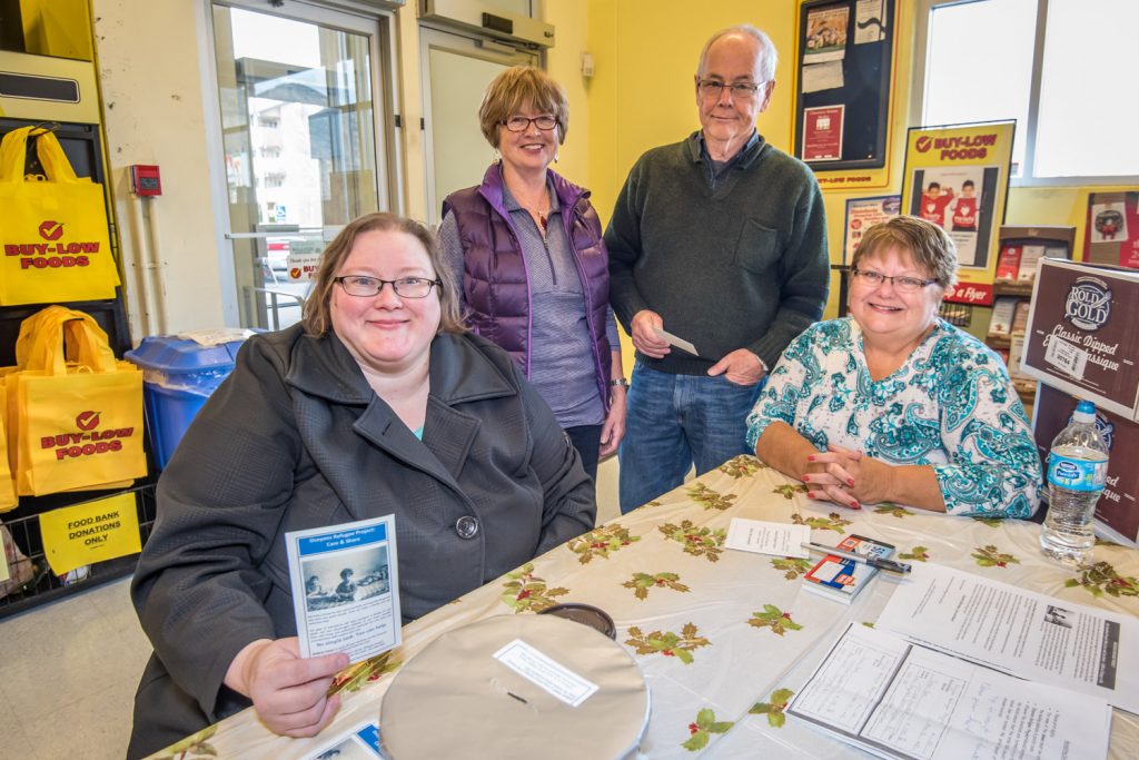 Lisa Ondejko Calder (left) and Eileen Hopkins (right) have taken on fundraising for the Osoyoos refugee project. Behind are volunteers Mary and Frank Halpin. They had a table set up at Buy-Low Foods on Friday and Saturday, shown here, and another at AG Foods. They plan to do it again next weekend. (Richard McGuire photo)