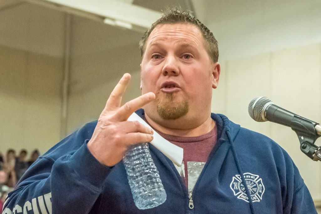 Chad Jensen gave up some of his speaking time to allow Brenda Dorosz, chair of Save Our Schools, to finish her presentation that was cut short by moderator Brian Pepper. He argued that cutting administrative positions would be preferable to closing a school. (Richard McGuire photo)