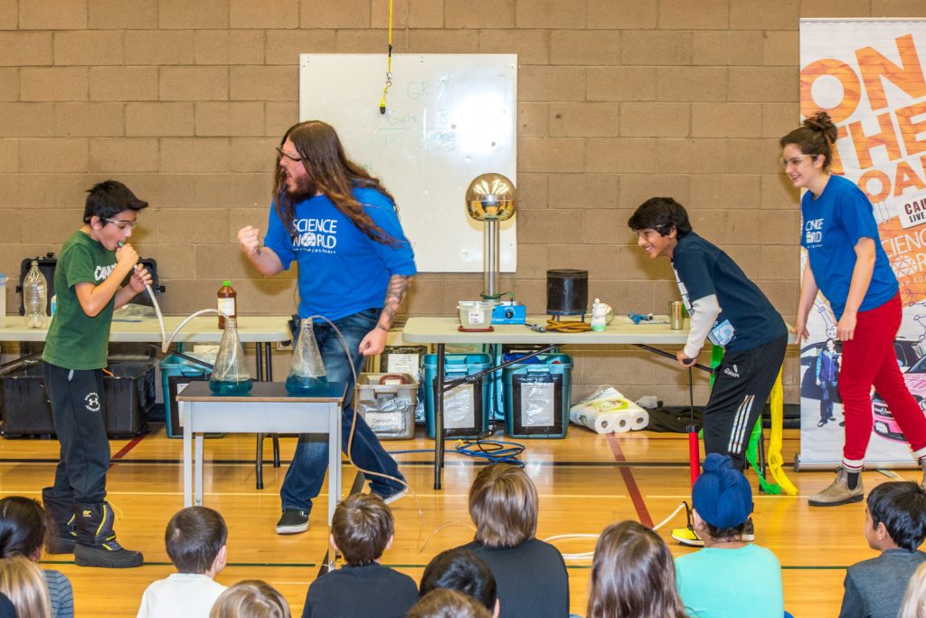 Stephan Adamus encourages Ash Kosaka to blow harder while Charlotte Swanson encourages Puneet Cheema to pump harder as the two students race to force air into beakers of bromothymol blue. Only Kosaka's liquid turns green because the carbon dioxide in his breath makes the water acidic. (Richard McGuire photo)