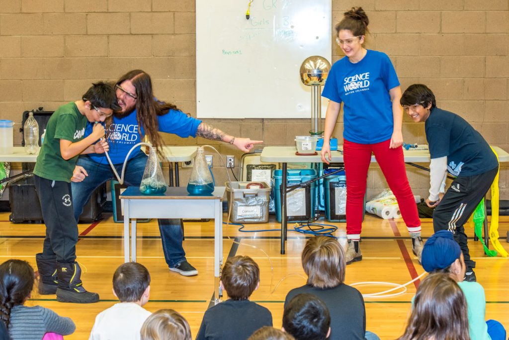Stephan Adamus encourages Ash Kosaka to blow harder while Charlotte Swanson encourages Puneet Cheema to pump harder as the two students race to force air into beakers of bromothymol blue. Only Kosaka's liquid turns green because the carbon dioxide in his breath makes the water acidic. (Richard McGuire photo)