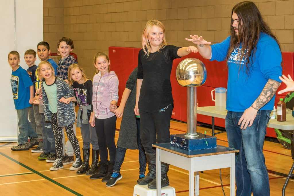 Stephan Adamus (right) encourages Emma Palmateer to put her hand on a Van de Graaf generator, which produces a low-voltage electricity current. She then links arms with other children, as her hair stands on end, sending the current down the chain of children. Also pictured are Rhune Gilbertson, Sehajvir Dhaliwal, Bryce Ogilvy, Paige Kaminski, Alesia Dortman and Paige Hanson. (Richard McGuire photo)
