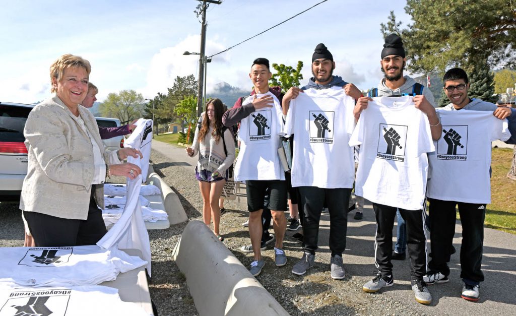 Osoyoos realtor Eileen McGinn was among the volunteers handing out T-shirts to students at Osoyoos Secondary School (OSS) Friday morning with the hashtag #OsoyoosStrong. The shirts were created by Jamie Elder of Unity Osoyoos, along with other volunteers. They are intended to show pride for education in Osoyoos. Proceeds raised from selling the shirts in the community will help to fund an independent community high school, which many in the community hope will fill the void left by the planned closure of OSS. (Richard McGuire photo)