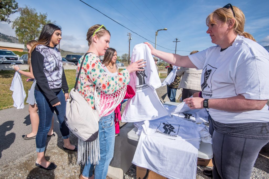 Brenda Dorosz (right), chair of the Save Our Schools committee, was among the volunteers handing out shirts to Osoyoos Secondary School students on Friday. The shirts, with the hashtag #OsoyoosStrong, were created by Jamie Elder of Unity Osoyoos, along with other volunteers. They are intended to show pride for education in Osoyoos. Proceeds raised from selling the shirts in the community will help to fund an independent community high school, which many in the community hope will fill the void left by the planned closure of OSS. (Richard McGuire photo)