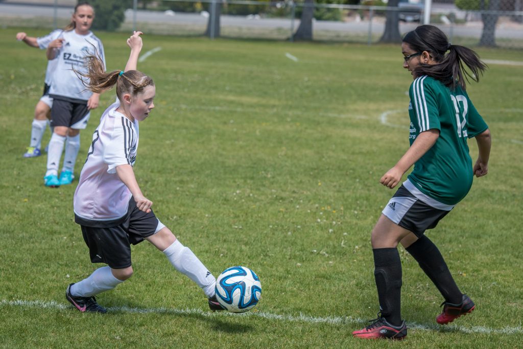 Sydney Hanson from the Osoyoos Under-13 girls squad tries to dribble around a defender from the Oliver Under-13 girls team this past Saturday afternoon at Tuc-el-Nuit Elementary School in Oliver. The girls from Oliver earned a tough 1-0 victory in Pinnacles Football Club league action. Minor soccer action takes place in Oliver and Osoyoos almost every weekend until late June. (Richard McGuire photo)