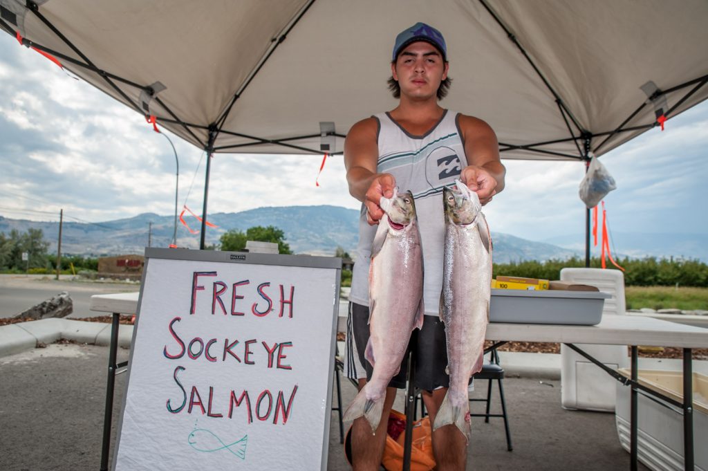 Tristan Baptiste-Hall sells freshly caught sockeye salmon from a stand at the Petro Canada station for the Nk'Mip Desert Cultural Centre. (Richard McGuire photo)